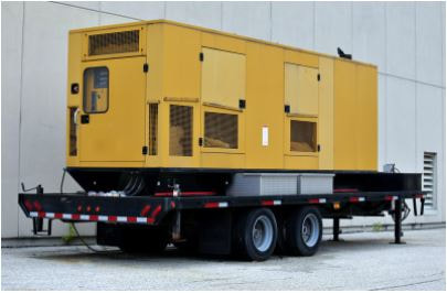 Commercial backup generator sitting on trailer bed on side of building
