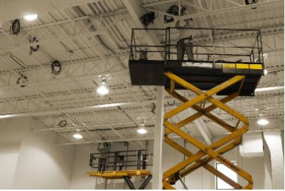 Electrician doing electrical repair inside commercial building on scissor lift